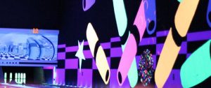 A wall graphic with blacklight-lit candlepin bowling pins.