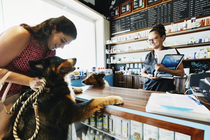Smiling pet store owner greeting pet owner and dog
