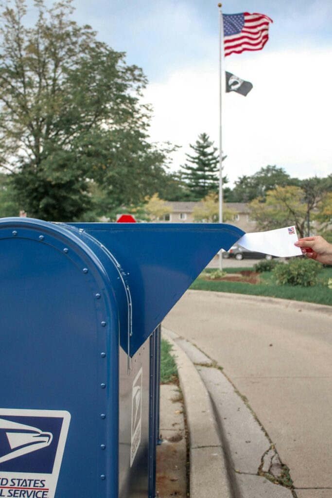 Hand inserting envelope into mailbox.