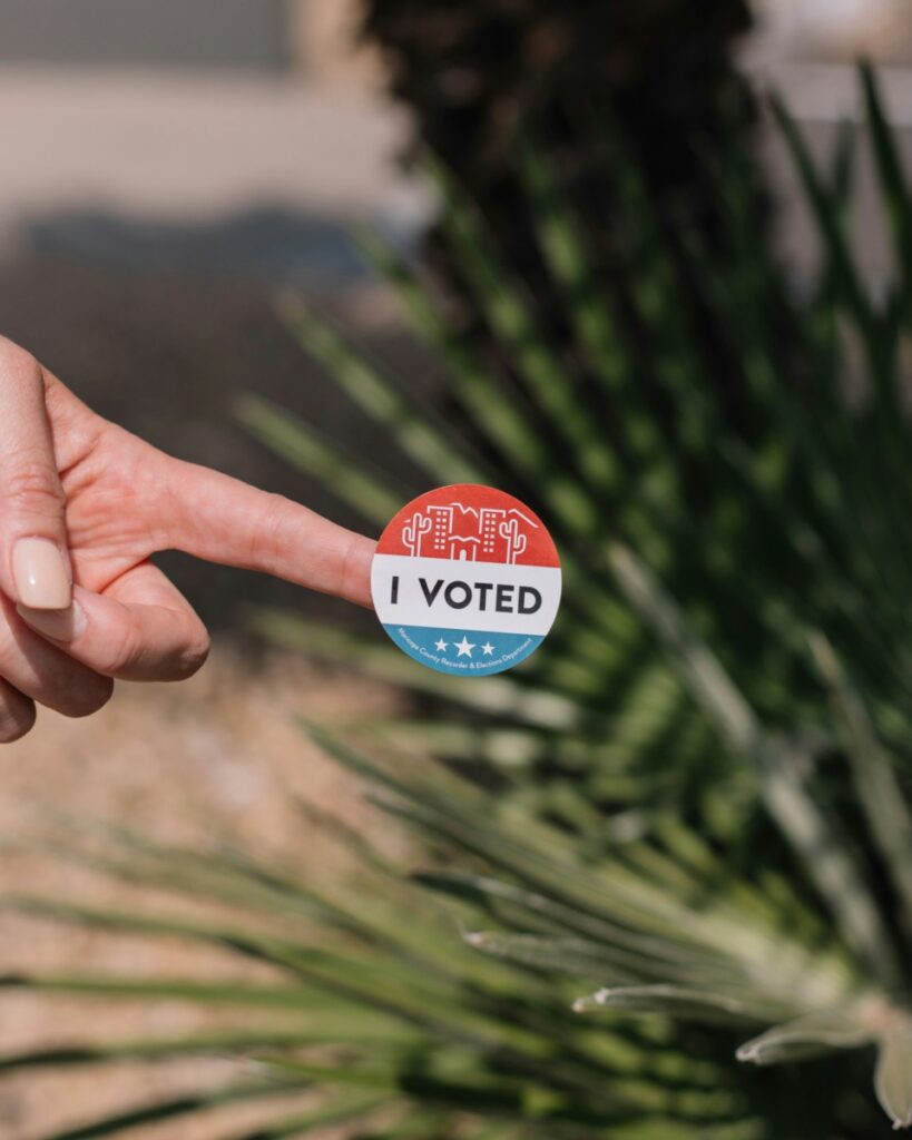 Round "I Voted" sticker on someone's pointer finger.