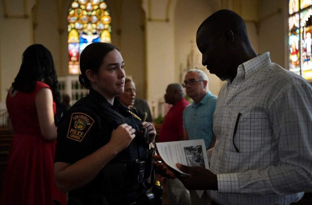 A Springfield police officer chats with parishioners after a service in support of the Haitian community at St. Raphael Catholic church in Springfield, Ohio, on September 15, 2024. (Luis Andres Henao/AP)