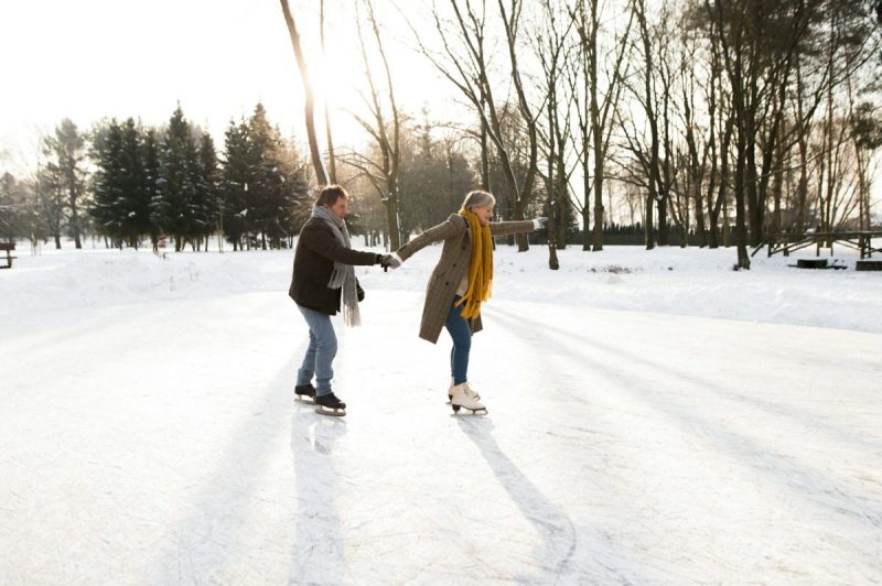 Older couple holding hands and figure skating.