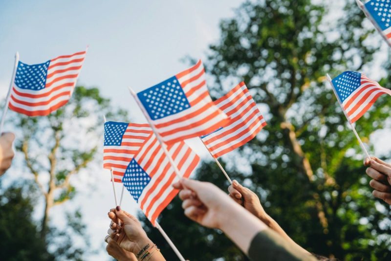 hands hold small american flags in celebration of america's independence day.
