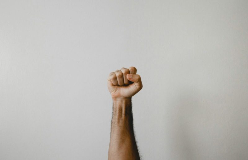 a white hand is raised in a fist against a white backdrop