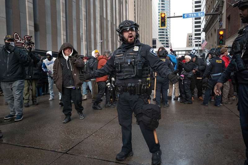 Photo of police officers and ICE officers in front of protesters.