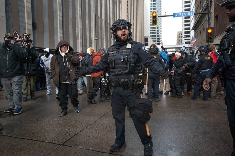 Photo of police officers and ICE officers in front of protesters.